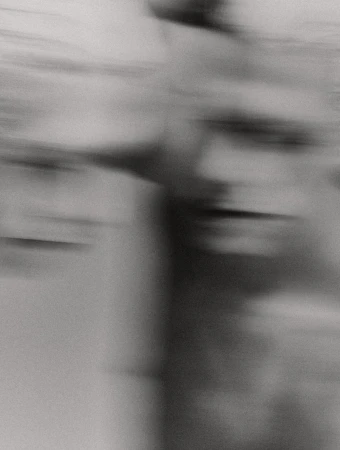 Abstract, monochromatic image with blurred figure, horizontal lines and movement; an adult torso is only partially visible with high contrast.