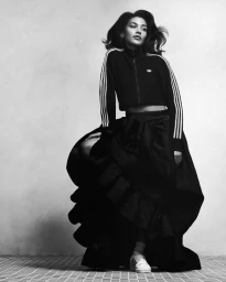 Model wearing a black Adidas track jacket and a voluminous skirt against a light background for Hotel Superstar