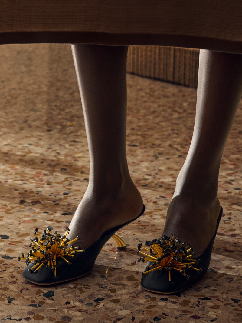 Close-up of Christy Turlington wearing embellished black mules with gold spike details for Salvatore Ferragamo
