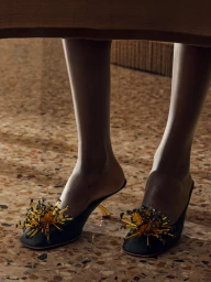 Close-up of Christy Turlington wearing embellished black mules with gold spike details for Salvatore Ferragamo