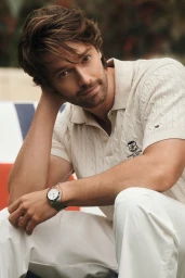 Patrick Schwarzenegger wearing an off-white cable knit polo shirt and white trousers for the Tommy Hilfiger campaign