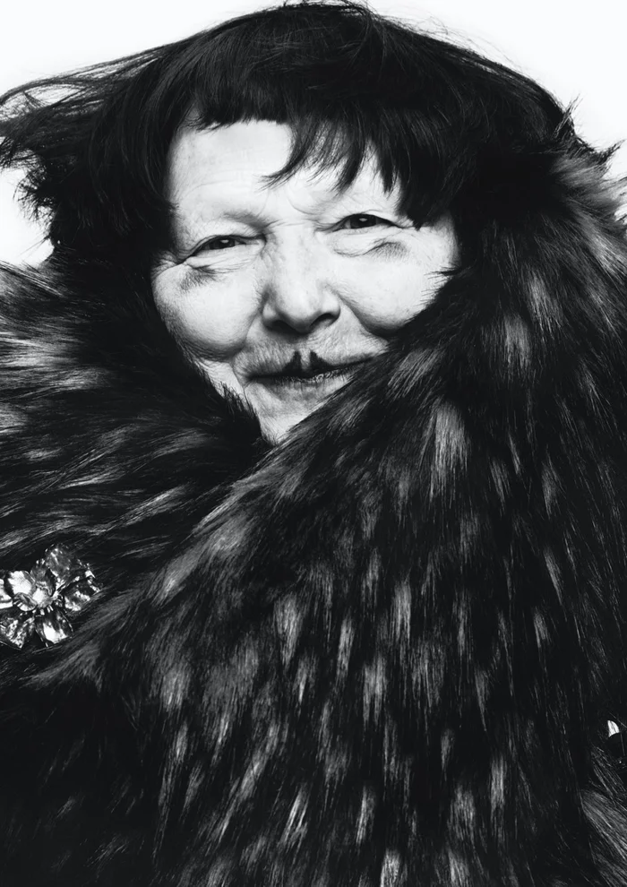 Close-up monochrome portrait of Lynn Yaeger wearing a dark faux fur collar against a white background