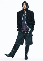 Model in black blazer and knee-high boots wearing a headscarf against a bright white background for H&M New York 2026