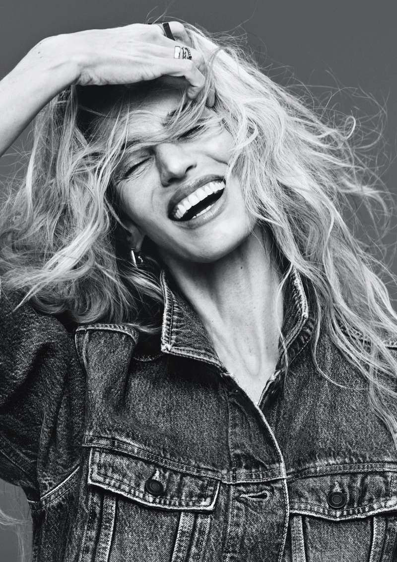Black and white portrait of a smiling woman with long flowing hair wearing a denim jacket, photographed by Rafael Pavarotti for H&M.