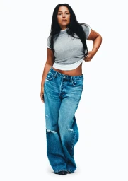 Model Paloma Elsesser wearing a grey t-shirt and loose blue denim jeans against a plain white background
