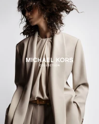 Model Mica Arganaraz in a neutral beige blazer and blouse against a white background for Michael Kors Spring 2026 campaign.