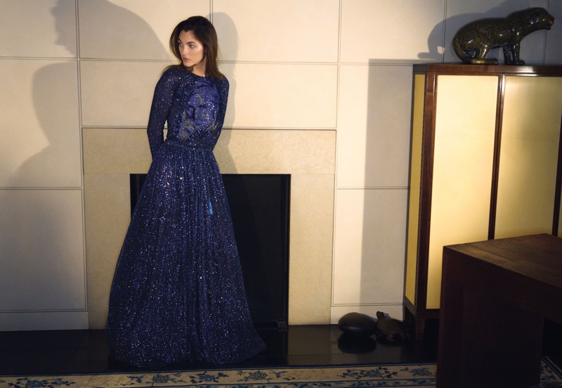 Vittoria Ceretti in a sparkly blue long-sleeved evening gown standing in front of a fireplace for Giorgio Armani.