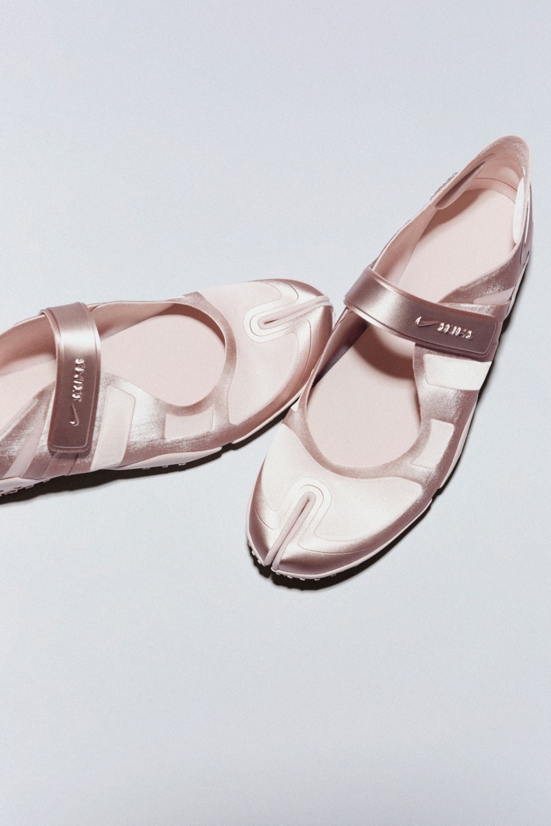 A pair of metallic rose gold Nike Air Rift Mary Jane-style split-toe shoes, angled against a plain, light grey background.