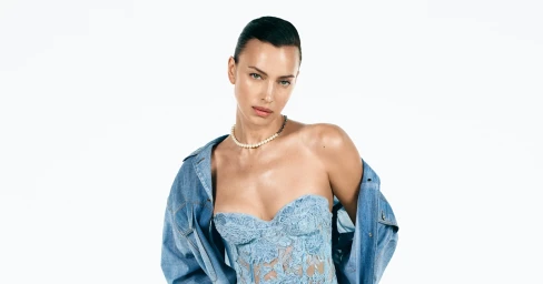 Model Irina Shayk wearing a blue lace strapless top and denim jacket against white