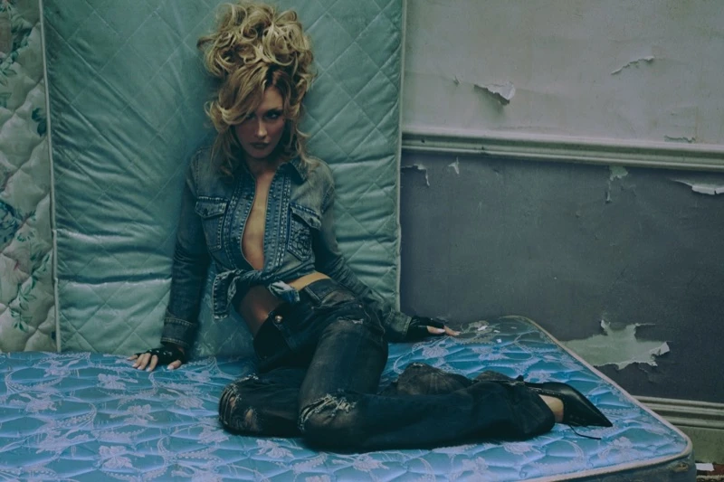 Bella Hadid in a denim outfit reclining on teal mattresses against a worn, peeling wall for the Miss Sixty campaign.