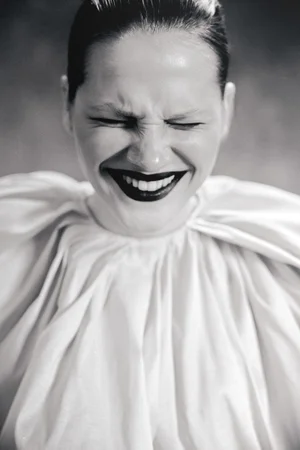 Black and white close-up portrait of a laughing woman wearing dark lipstick and a voluminous gathered white collar.