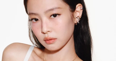 Close-up portrait of Jennie wearing stacked metallic ear cuffs and delicate necklaces against a plain white background for Chanel Coco Crush.