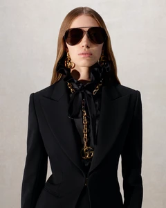 Model Mariacarla Boscono in black blazer and sunglasses wearing chunky gold jewelry for Gucci La Famiglia campaign