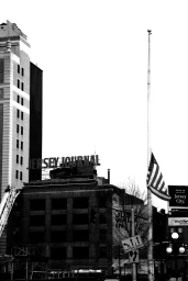 Black and white editorial image of the Jersey Journal building exterior featuring an American flag on a tall flagpole
