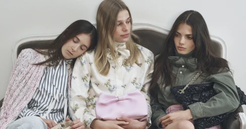 Three female models seated on a vintage sofa holding designer handbags for the Dior Spring-Summer 2026 campaign.