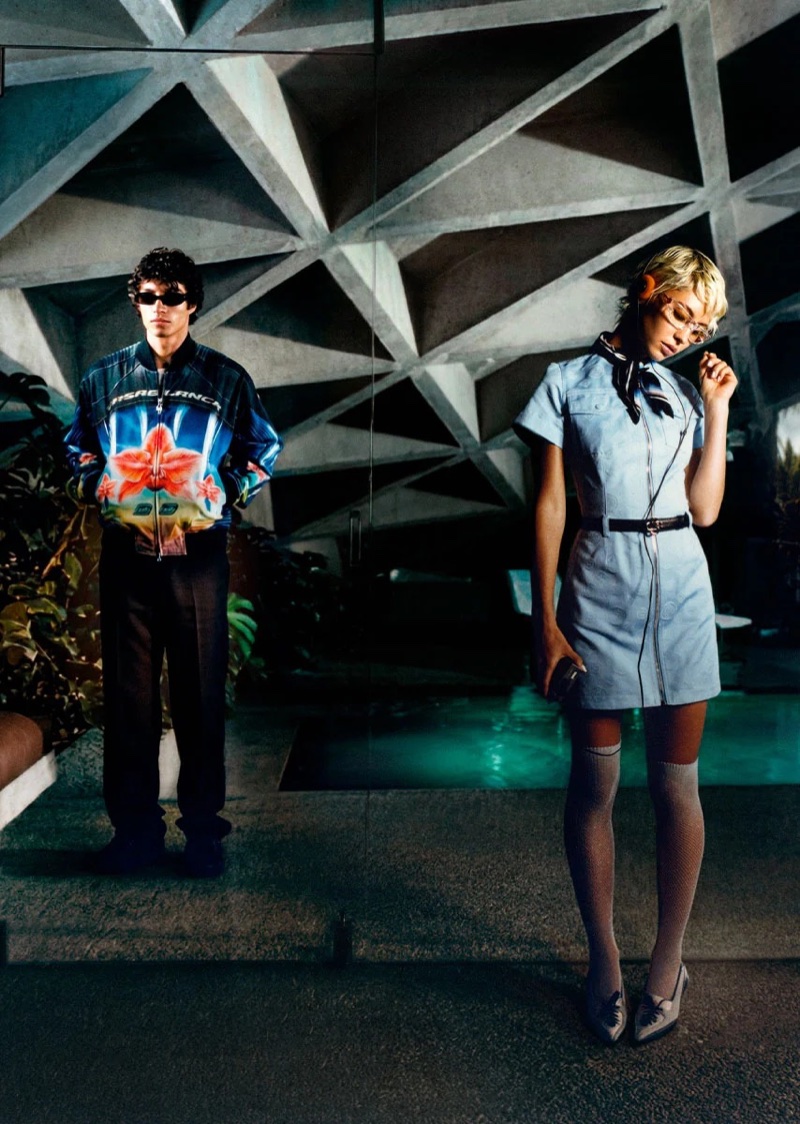 Model Iris Law in light blue uniform dress standing near indoor pool beneath geometric concrete ceiling by Corentin Leroux for Casablanca.