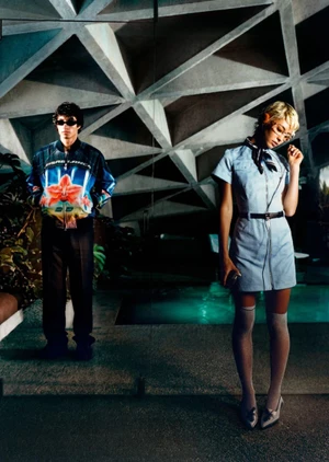 Model Iris Law in light blue uniform dress standing near indoor pool beneath geometric concrete ceiling by Corentin Leroux for Casablanca.