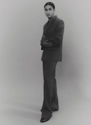 Model Kevin Nyavedji wearing a dark suit against a grey seamless background for 032c project I Would Prefer Not To