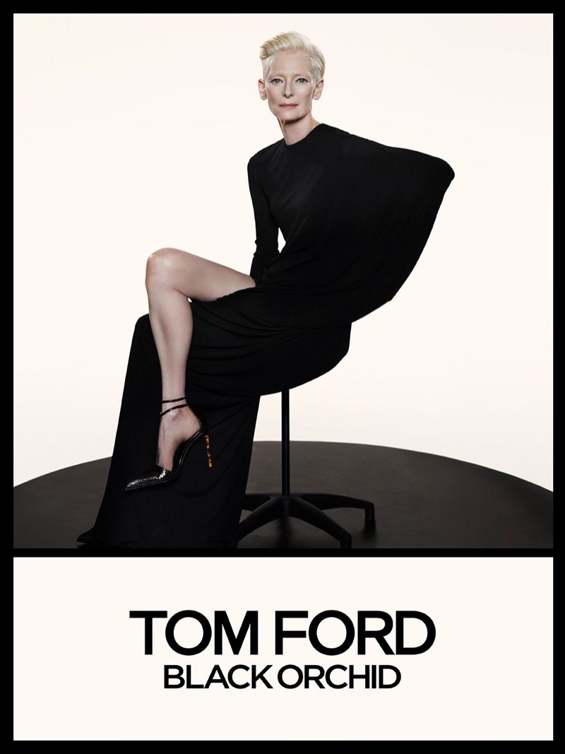 Tilda Swinton in a sculptural draped black gown seated on a swivel chair for Tom Ford Black Orchid campaign.