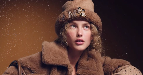 Model Dorit Revelis wearing a brown furry hat and coat for Max Mara Holiday 2025 campaign amidst falling snow.