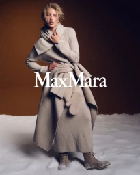 Model Dorit Revelis in beige winter knitwear with a scarf and boots in a snow setting for Max Mara