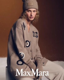 Model Dorit Revelis wearing a beige knit cardigan and matching beanie for Max Mara Holiday 2025 campaign
