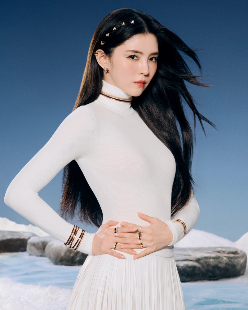 Han So-hee wearing Boucheron gold jewelry and a high-neck white dress against a snowy winter landscape backdrop.