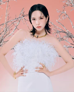 Mina wearing a white feathered top and gold jewellery against a pink background with silver frost branches for Boucheron.