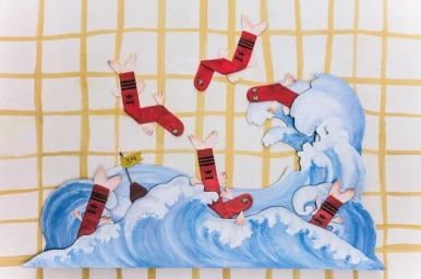 Paper art sculpture of red Adidas socks shaped like fish swimming in painted blue waves against a yellow grid background