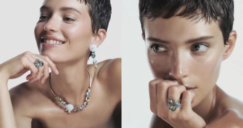 Model with short dark hair wearing a gemstone necklace and floral earrings against a white background for Giorgio Armani