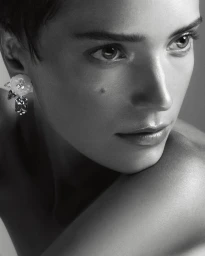 Close-up portrait of a woman wearing floral crystal earrings against a neutral studio background.
