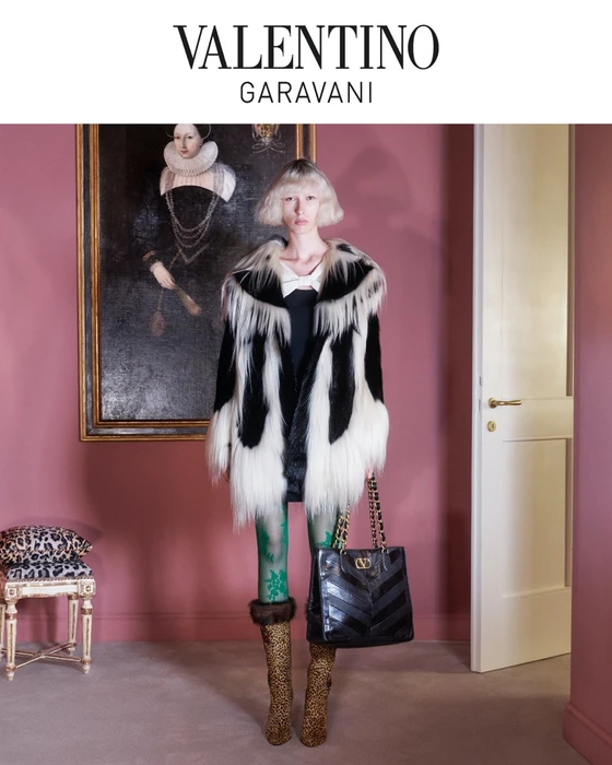 Model with blonde bob wearing a black and white fur coat, green patterned tights, and leopard print boots holding a black handbag.