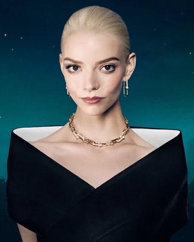 Anya Taylor-Joy wearing a gold necklace and black dress against a dark teal background for Tiffany and Co.