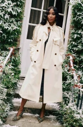 Naomi Campbell wearing a cream trench coat standing on a snowy porch for Burberry photographed by Angelo Pennetta