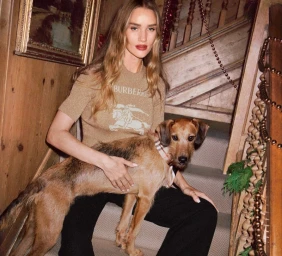 Rosie Huntington-Whiteley seated on a wooden staircase with a dog for Burberry, photographed by Angelo Pennetta.