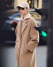 Model Edie Campbell in a camel coat, cap and sunglasses standing on a city street for Max Mara Icons 2025