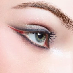 Close-up eye makeup featuring shimmering eyeshadow and red winged eyeliner on a woman from Chanel Holiday 2025 campaign.