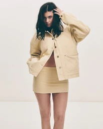 Kylie Jenner wearing a light yellow jacket and skirt against a solid white studio background.