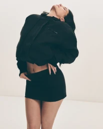 Kylie Jenner wearing a black hoodie and mini skirt against a white studio background for Khy Canvas Collection