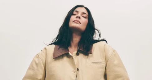 Kylie Jenner wearing a beige jacket with a brown collar against a plain white background