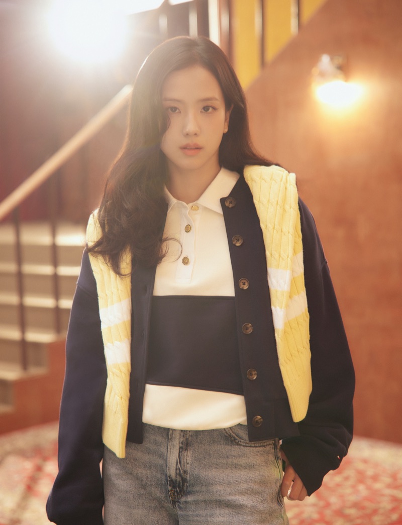Jisoo wearing a navy cardigan over a polo shirt and jeans for Tommy Hilfiger in a warmly lit indoor setting