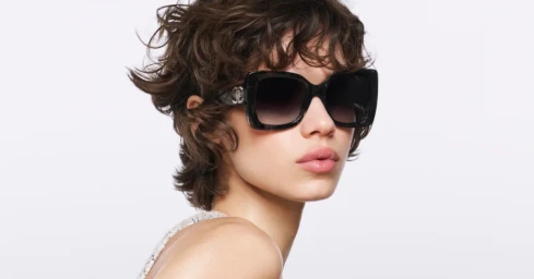 Model Mathilda Gvarliani wearing dark square sunglasses with a tweed strap against a clean white background for Chanel.
