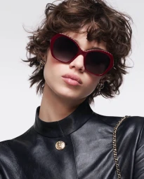 Model Mathilda Gvarliani wearing red sunglasses and a black leather jacket against a plain white background for Chanel.