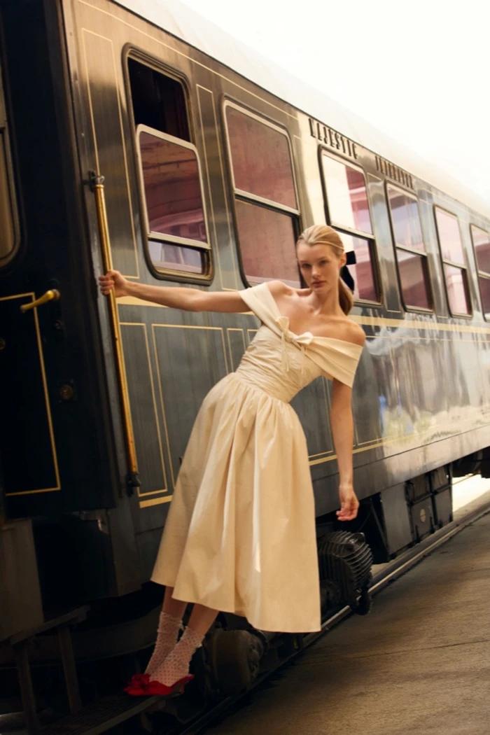 Kris Grikaite posing on a vintage train for For Love & Lemons Winter 2025 campaign, photographed by Camilla Akrans.