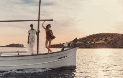 Two models on a white wooden boat on the water during sunset for Zimmermann Resort Swim 2026 campaign.