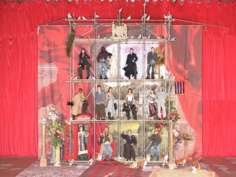 Models posed across multiple levels of scaffolding against a dramatic red curtain and painted classical backdrop for H&M.