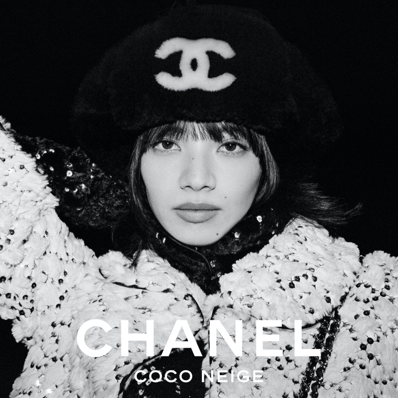 Monochrome portrait of Nana Komatsu wearing a furry black beret with the Chanel logo and a textured winter coat.
