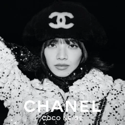 Monochrome portrait of Nana Komatsu wearing a furry black beret with the Chanel logo and a textured winter coat.