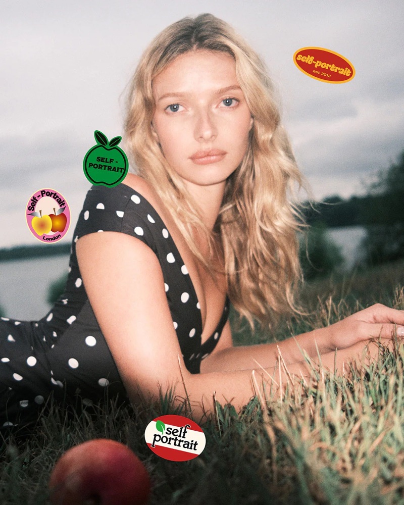 Model Apple Martin in black polka dot dress lying in grass for Self-Portrait Fall-Winter 2025 campaign shot by Ryan McGinley.