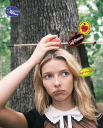 Model Apple Martin balancing an apple pierced by an arrow on her head in a woodland setting for Self-Portrait Fall-Winter 2025 campaign.